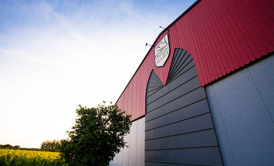 Low angle shot of the entrance to the large red and grey shed with the Domaine Alliet logo at the top