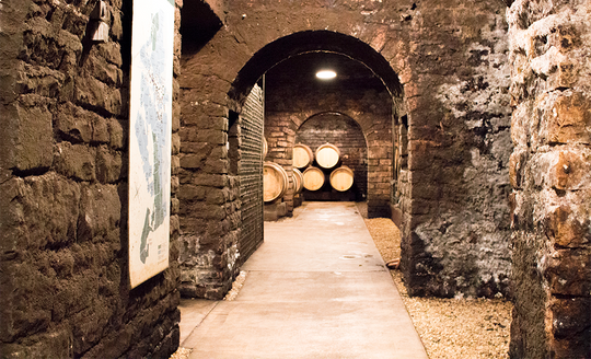 Underground stone cellar with barrels of wine aging in Domaine Roulot