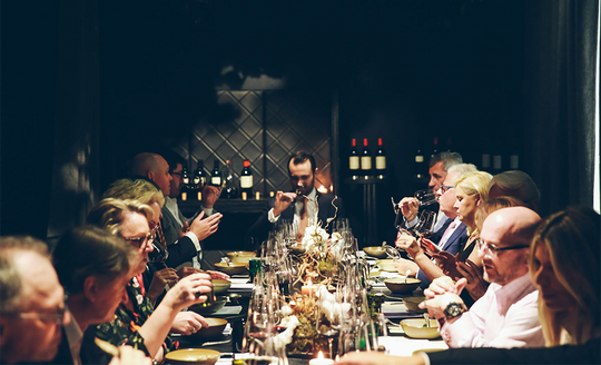 Alex Rougeot hosting a wine dinner for a full table of guests tasting wines with delicious meals