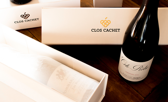 Neat wine boxes with the Clos Cachet Logo on them with a bottle of wine next to them