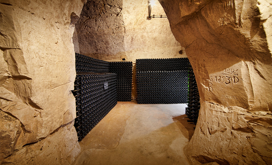 Sandstone room filled with rows and rows of wine bottles in Domaine Pierre Paillard